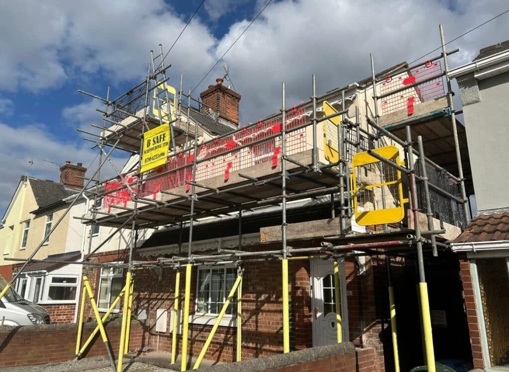 Scaffolding erected around a two-storey terraced house during roof and chimney renovation works