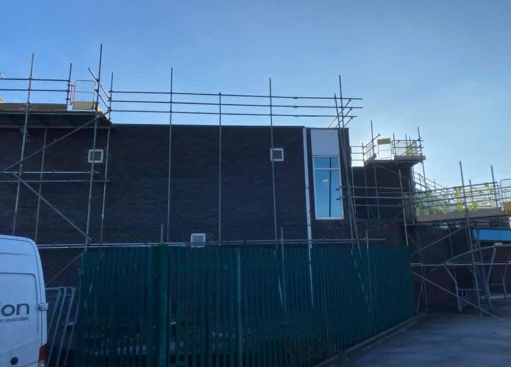 Professional commercial scaffolding by B Safe Limited around a concrete and brick property