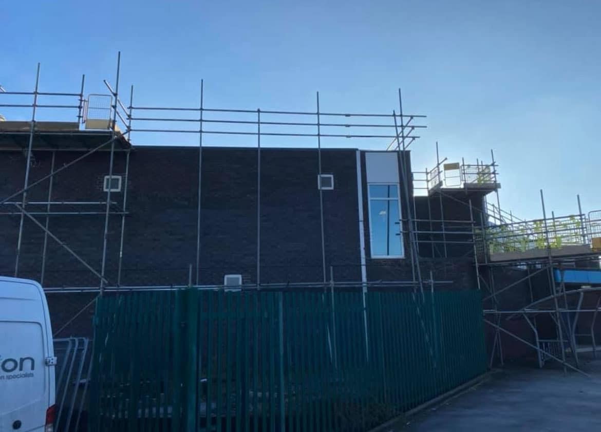 Professional commercial scaffolding by B Safe Limited around a concrete and brick property