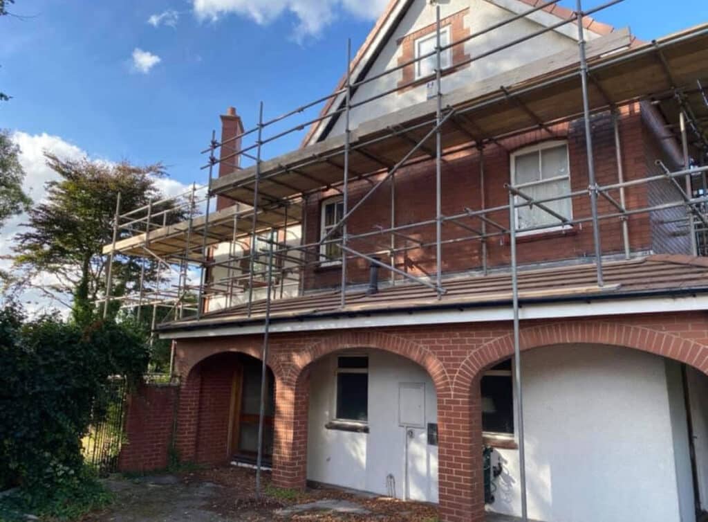 View of construction scaffolding enclosing the front elevation of a UK brick-built home BSafe