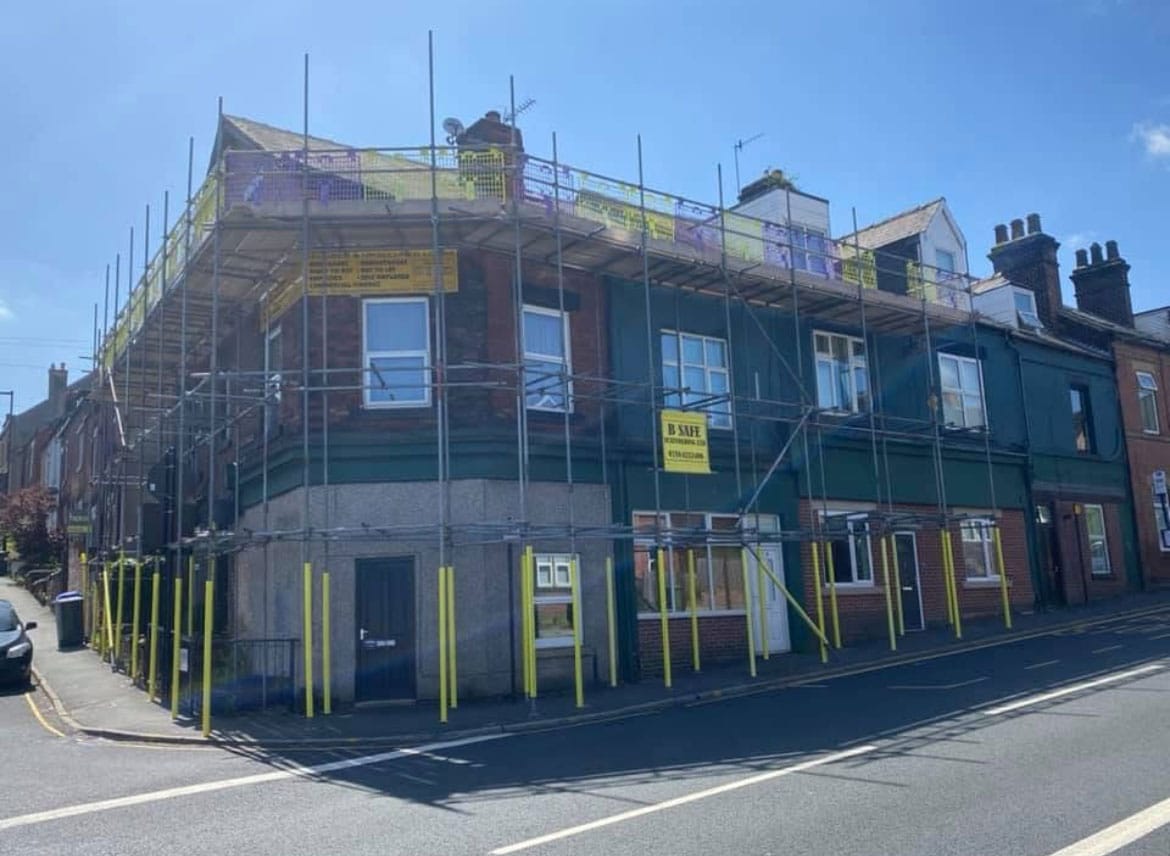 UK scaffolding project: tall scaffolding with blue protective mesh covering a concrete-framed building